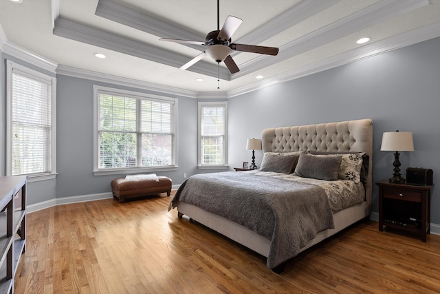 bedroom with crown molding, baseboards, wood finished floors, and a raised ceiling