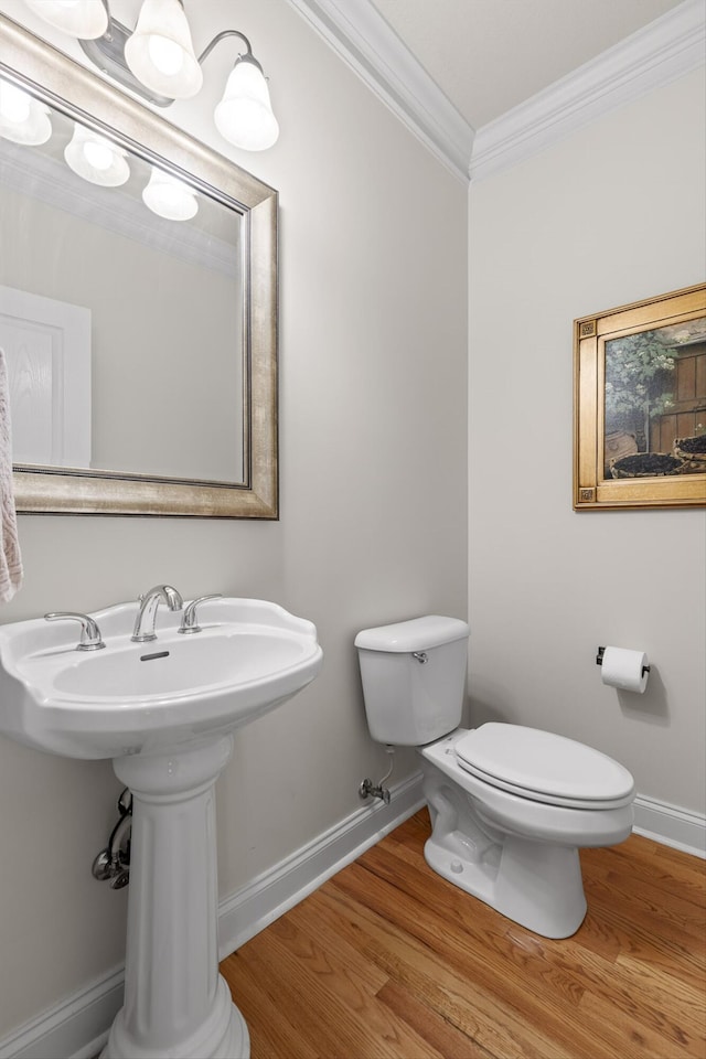 bathroom featuring baseboards, ornamental molding, wood finished floors, and toilet