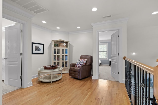 living area featuring visible vents, ornamental molding, light wood finished floors, and baseboards