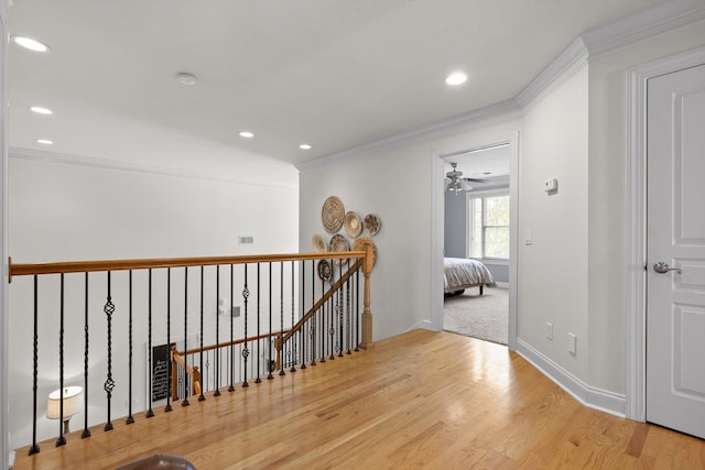 hallway with ornamental molding, recessed lighting, wood finished floors, and an upstairs landing