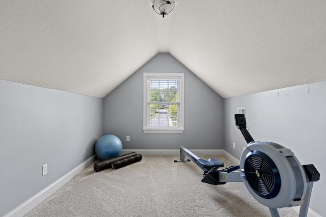 exercise area featuring carpet floors, baseboards, and vaulted ceiling
