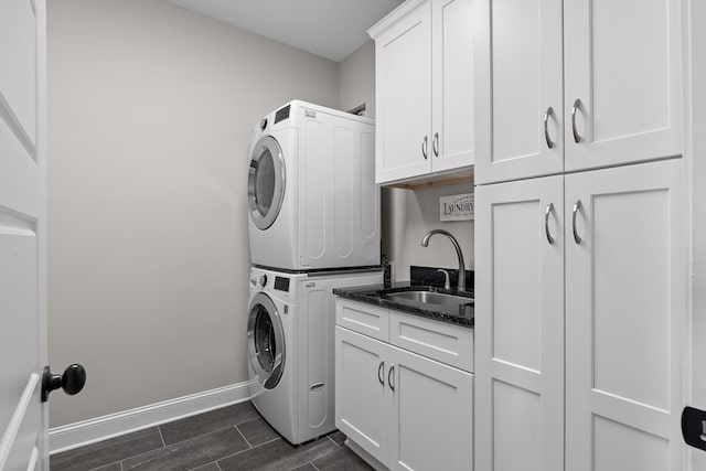 7407 Pond Vw, Harrison, TN 37341 - washroom featuring stacked washer and dryer, wood finish floors, cabinet space, a sink, and baseboards