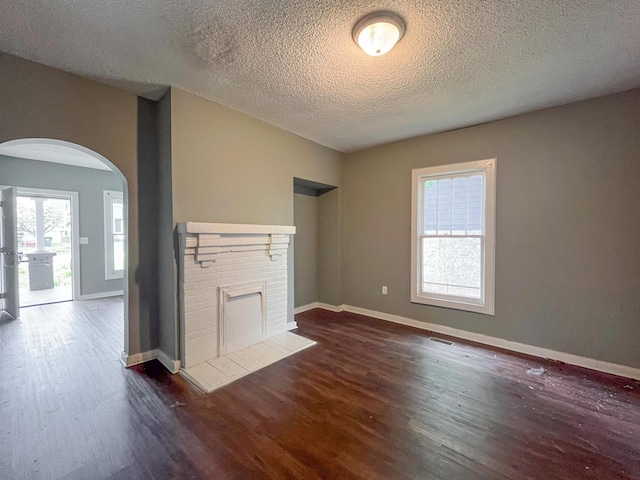 1241 E 35th St, Chattanooga, TN 37407 - unfurnished living room featuring baseboards, arched walkways, dark wood-style floors, and a fireplace