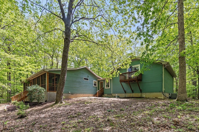 view of side of home with a sunroom, cooling unit, stairway, and entry steps
