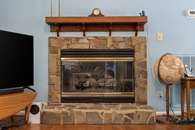 details featuring a stone fireplace and wood finished floors