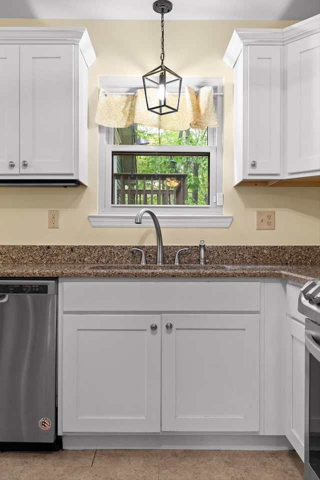 kitchen with white cabinets, a sink, dark stone countertops, stainless steel appliances, and decorative light fixtures