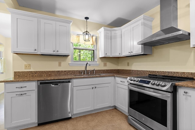 kitchen with wall chimney range hood, appliances with stainless steel finishes, hanging light fixtures, a sink, and white cabinetry