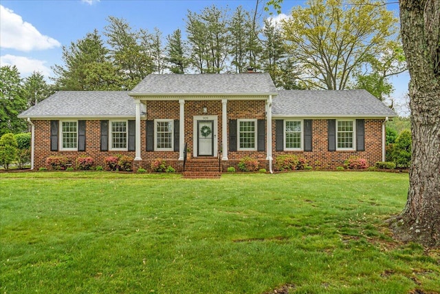 view of front of home with brick siding, a chimney, and a front yard