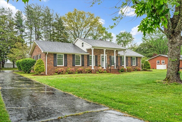 neoclassical / greek revival house featuring brick siding, a chimney, a shingled roof, and a front lawn