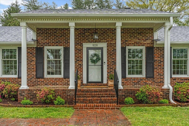 doorway to property with brick siding and a shingled roof