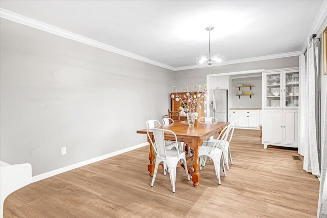 dining room featuring crown molding, light wood-style flooring, a chandelier, and visible vents