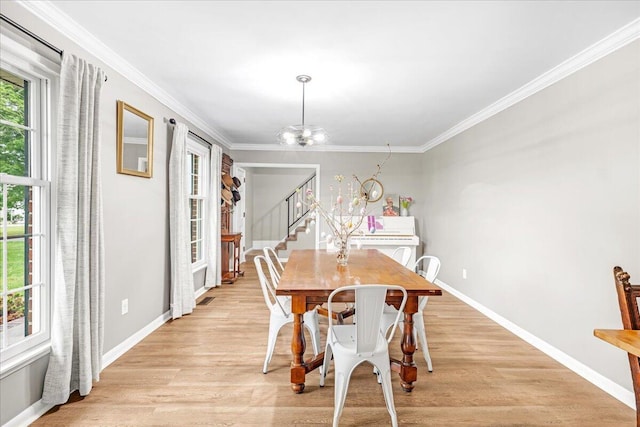 dining area featuring crown molding, light wood-type flooring, stairs, and a chandelier