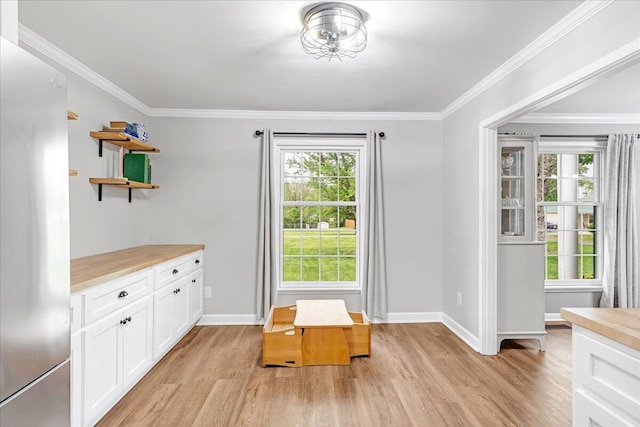 doorway featuring baseboards, ornamental molding, and light wood-style flooring