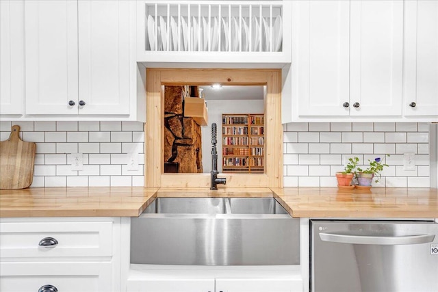 kitchen with white cabinets, a sink, butcher block counters, and dishwasher