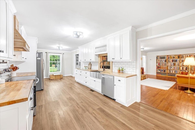 kitchen featuring butcher block countertops, appliances with stainless steel finishes, a sink, and light wood-type flooring