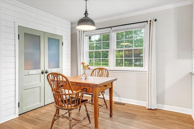 dining room with baseboards, visible vents, ornamental molding, and light wood finished floors