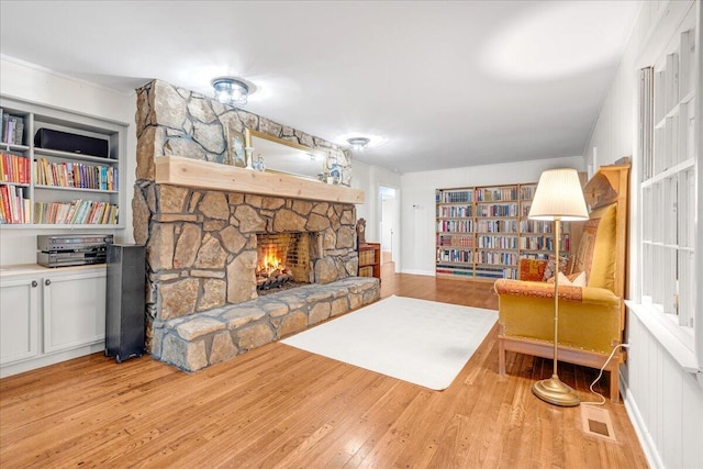 living area with a stone fireplace, wood finished floors, and visible vents