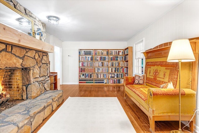sitting room with baseboards, ornamental molding, wood finished floors, and a fireplace