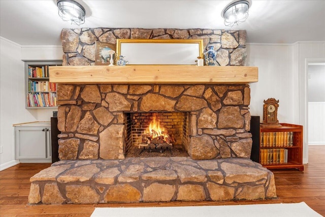 details with baseboards, ornamental molding, wood finished floors, and a fireplace