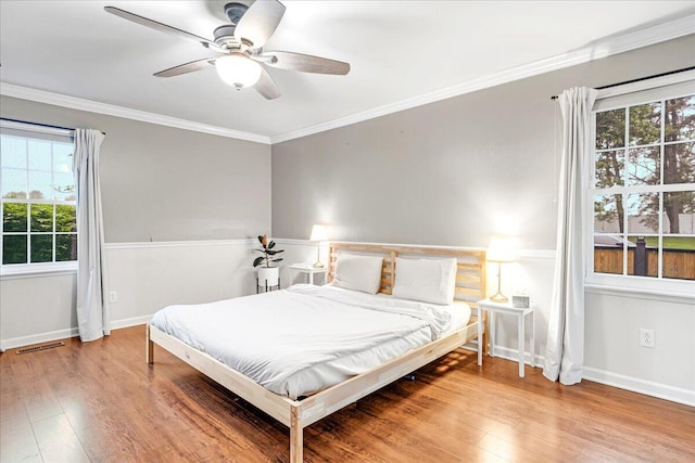 bedroom featuring visible vents, multiple windows, and wood finished floors