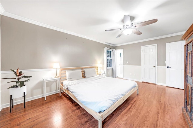 bedroom featuring crown molding, wainscoting, and light wood-type flooring