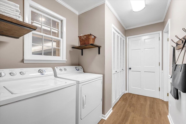 clothes washing area with laundry area, ornamental molding, baseboards, light wood-type flooring, and washing machine and dryer