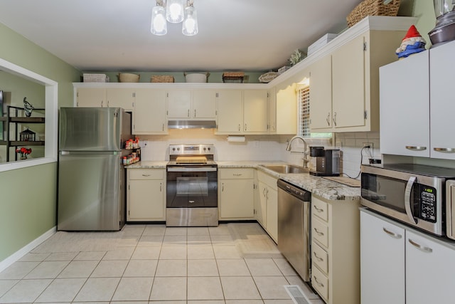 2031 Millard Rd, Soddy Daisy, TN 37379 - kitchen featuring a sink, under cabinet range hood, light tile patterned floors, tasteful backsplash, and appliances with stainless steel finishes