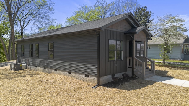 view of side of home featuring cooling unit, roof with shingles, and crawl space