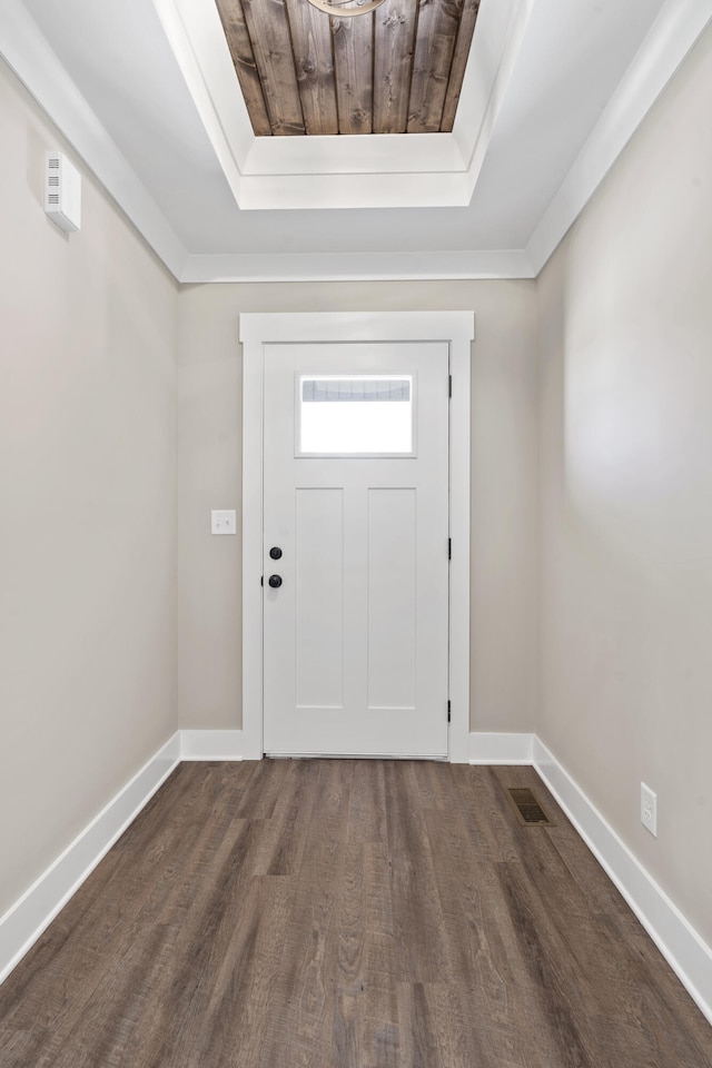 foyer entrance featuring visible vents, baseboards, a tray ceiling, and dark wood-type flooring
