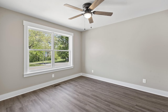 spare room with visible vents, a ceiling fan, baseboards, and dark wood finished floors