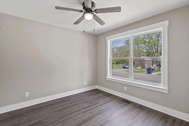 unfurnished room featuring dark wood-type flooring, visible vents, a ceiling fan, and baseboards