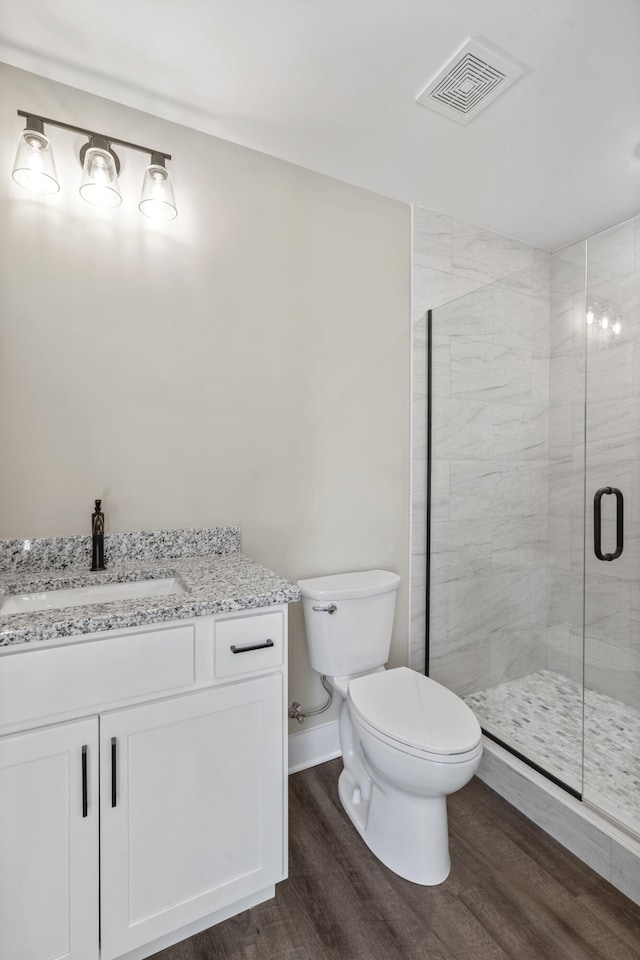 bathroom featuring wood finished floors, a stall shower, vanity, toilet, and visible vents