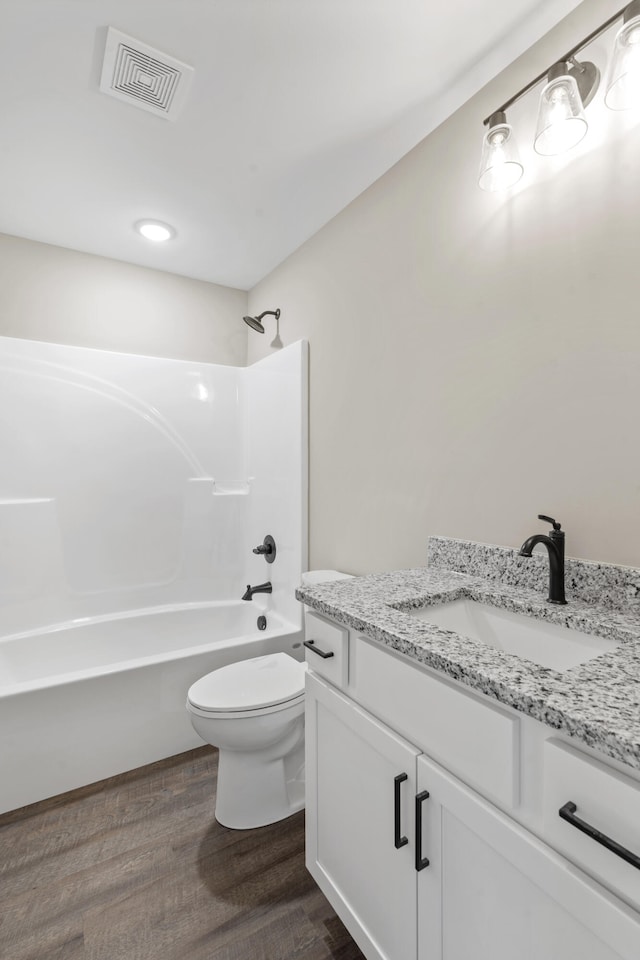 bathroom featuring wood finished floors, vanity, bathtub / shower combination, toilet, and visible vents