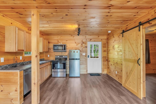 144 Hambright Rd, Reliance, TN 37369 - kitchen with dark countertops, stainless steel appliances, a barn door, light brown cabinetry, and wood finished floors