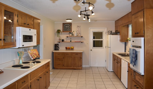 kitchen with white appliances, brown cabinetry, light tile patterned floors, light countertops, and ornamental molding