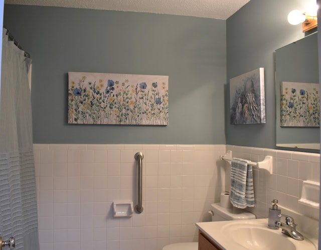 bathroom featuring wainscoting, a shower with curtain, tile walls, toilet, and a textured ceiling