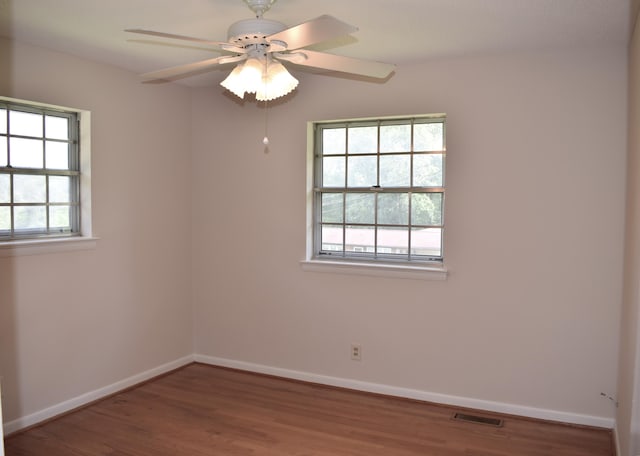 unfurnished room featuring a healthy amount of sunlight, visible vents, and baseboards