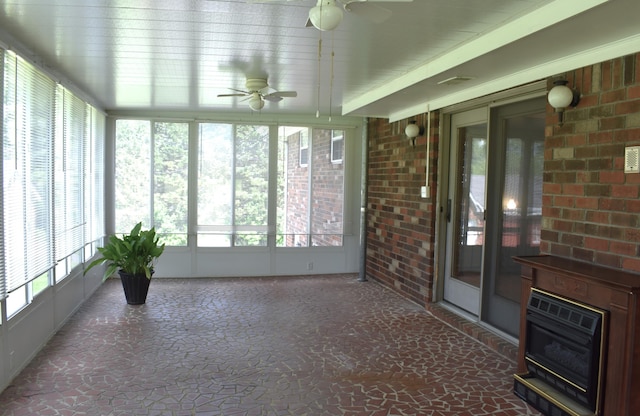 unfurnished sunroom with heating unit, brick wall, and a healthy amount of sunlight