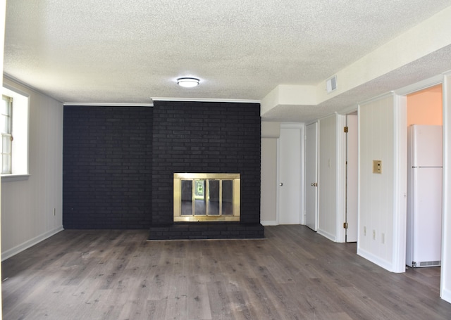 unfurnished living room with a brick fireplace, visible vents, baseboards, a textured ceiling, and wood finished floors