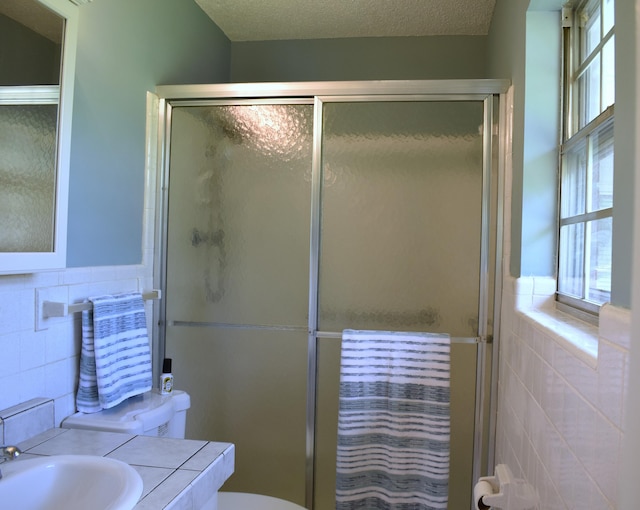 bathroom featuring tile walls, a wainscoted wall, toilet, vanity, and a stall shower