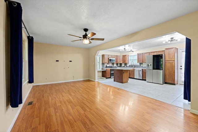 unfurnished living room featuring a sink, visible vents, baseboards, and light wood-type flooring