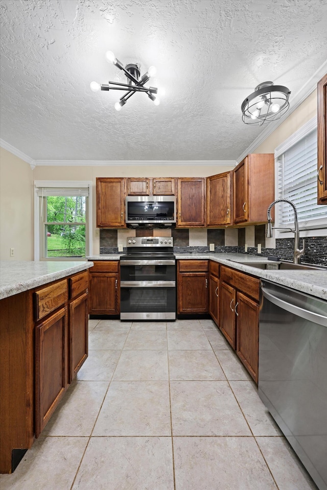 kitchen with a sink, stainless steel appliances, crown molding, light countertops, and a textured ceiling