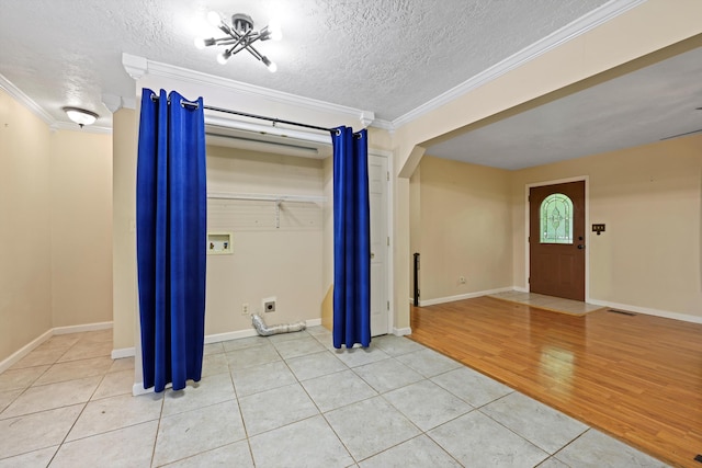 foyer with light tile patterned floors, a textured ceiling, visible vents, and ornamental molding