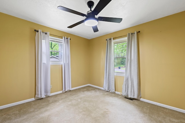empty room with visible vents, ceiling fan, carpet, and baseboards