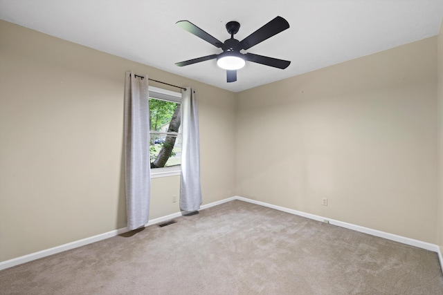 carpeted empty room with baseboards, visible vents, and a ceiling fan