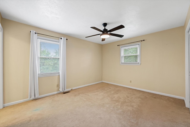 unfurnished room with visible vents, light carpet, and ceiling fan