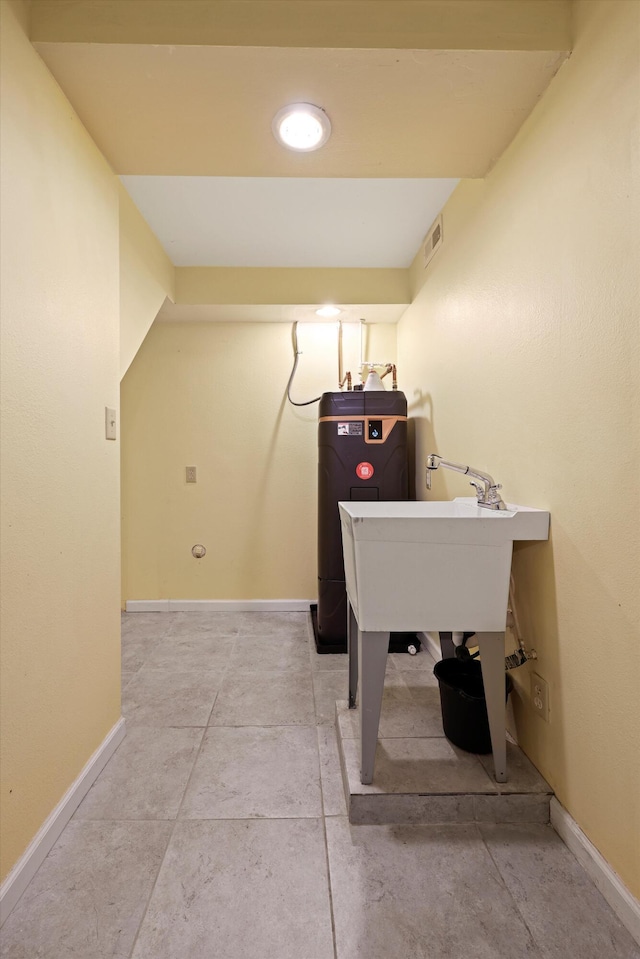 laundry room with baseboards, visible vents, and water heater
