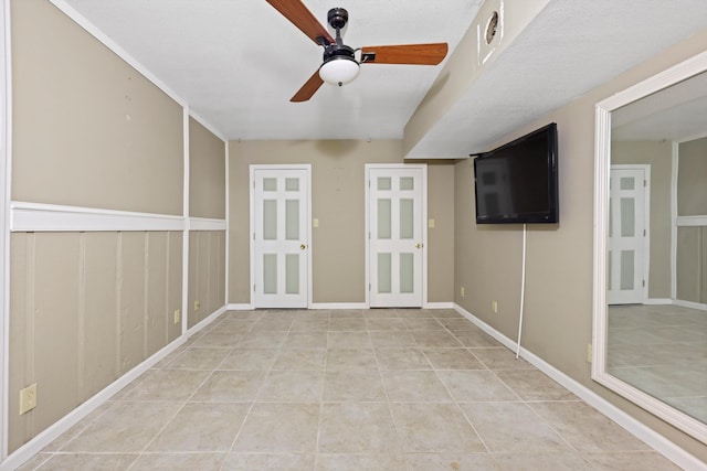 empty room with light tile patterned floors, a ceiling fan, and baseboards