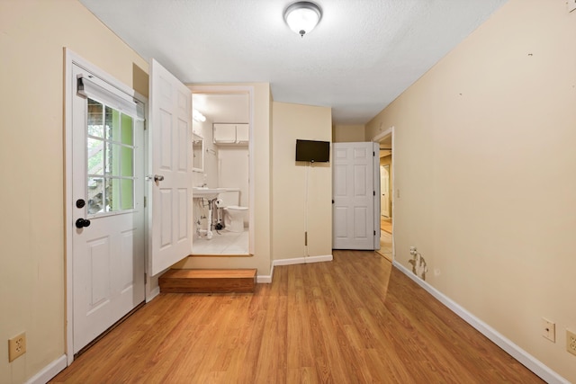 doorway featuring light wood finished floors and baseboards