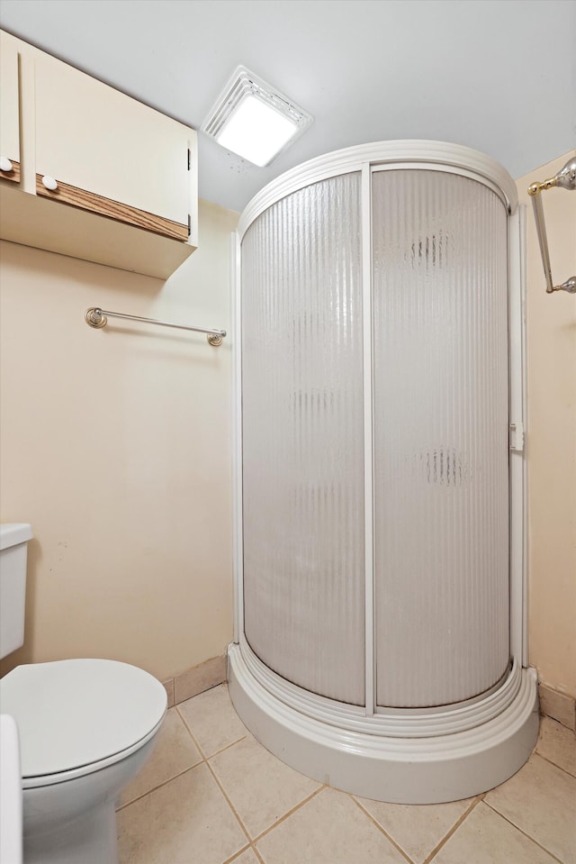 full bath featuring toilet, tile patterned flooring, a stall shower, and baseboards